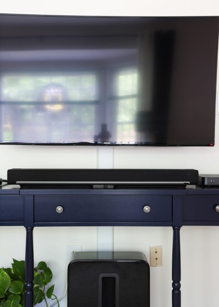 Navy blue console table underneath a wall-mounted television.