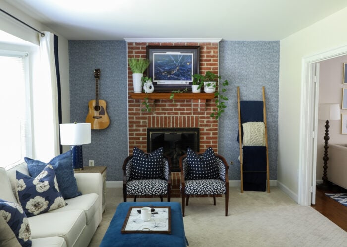 Navy and white family room with white couch, blue ottoman, and blue wallpaper