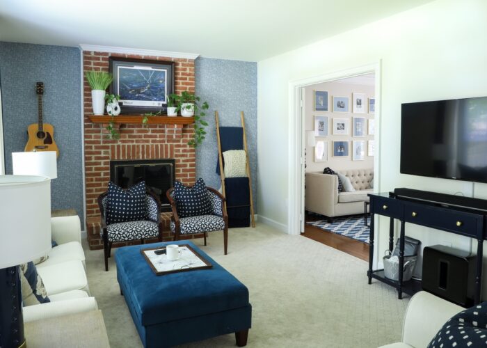 Navy and white family room with white couch, blue ottoman, and blue wallpaper