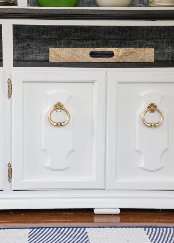 A white china hutch shown with clean brass knobs and hinges