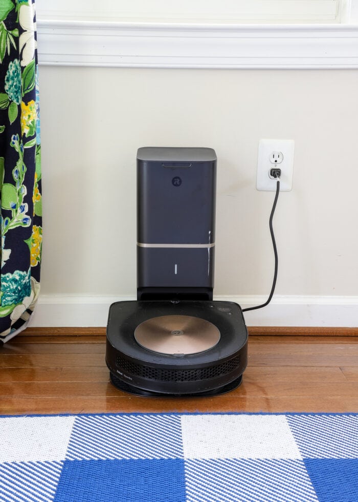 A robot vacuum on hardwood floors plugged into the wall