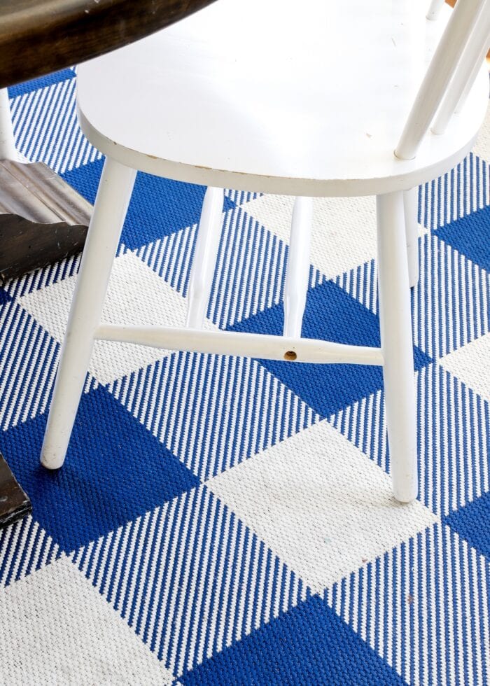 White chairs on top of a blue-and-white checked outdoor rug