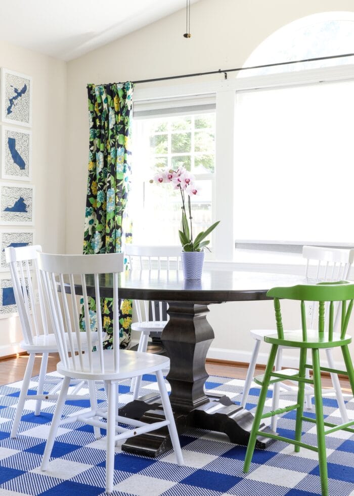 Dining Room in a sunroom, with blue and white rug, dark table, and floral drapes
