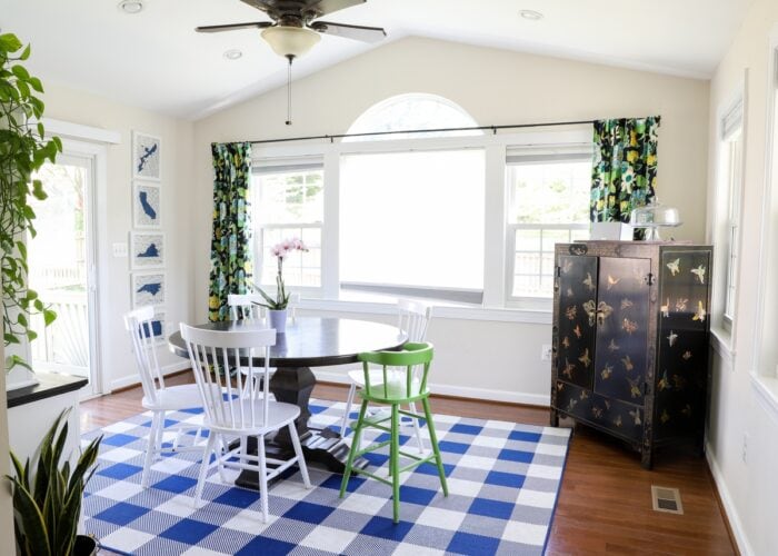 Dining Room in a sunroom, with blue and white rug, dark table, and floral drapes