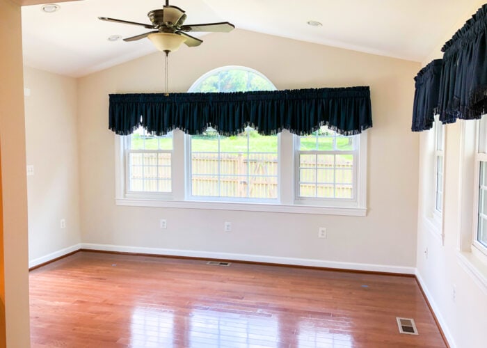 Empty sunroom with beige walls and blue fringe curtains