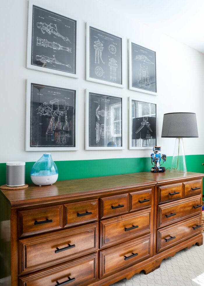 Wooden dressers against green wall with Star Wars prints hung above