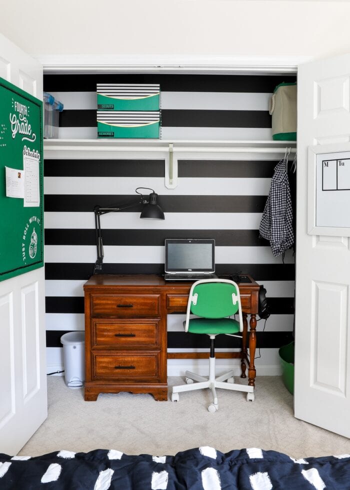 Black and white striped wallpaper inside a closet with a desk