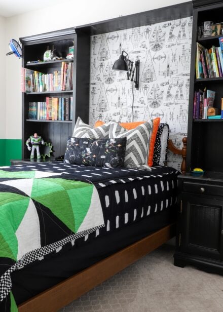 Wooden twin bed with black bedding and black bookshelves