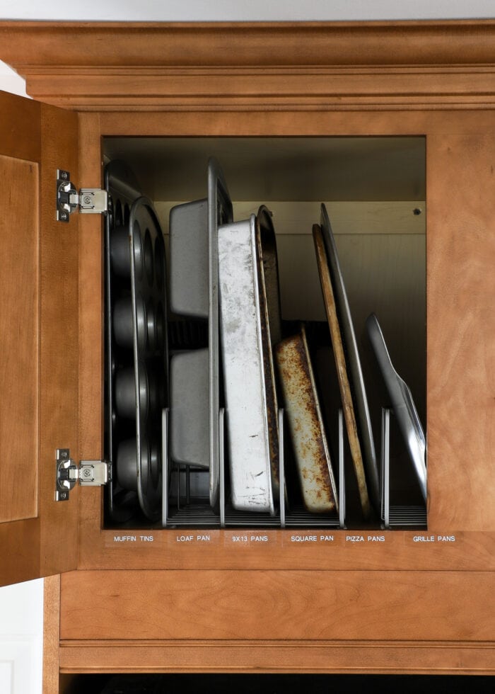 Cabinet above refrigerator organized to hold pans