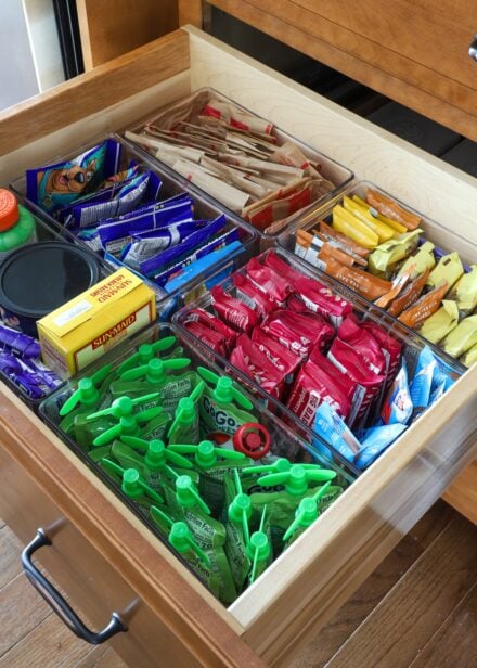Kitchen drawer organized with clear bins holding snacks
