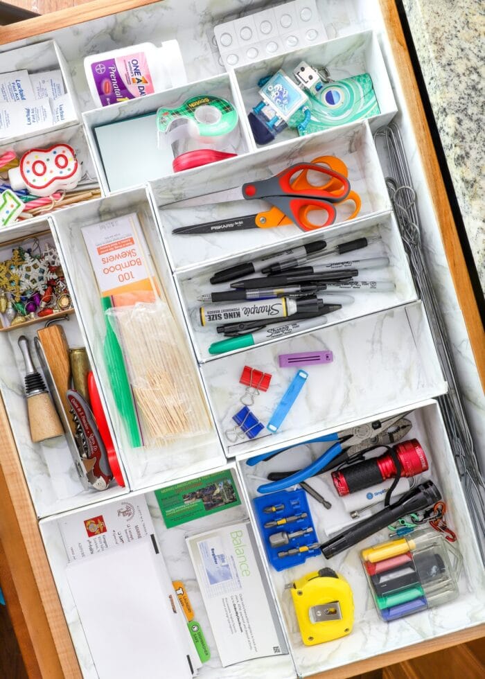 Junk drawer organized with cardboard boxes wrapped in marble paper