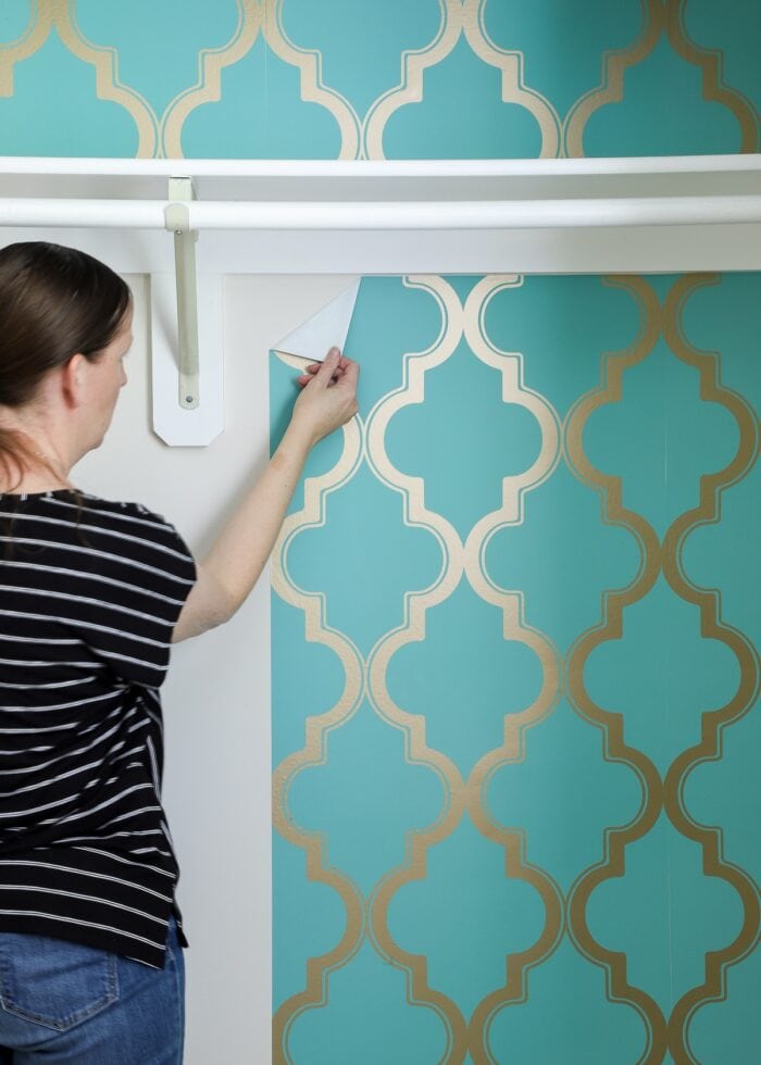 Hand pulling down peel-and-stick wallpaper
