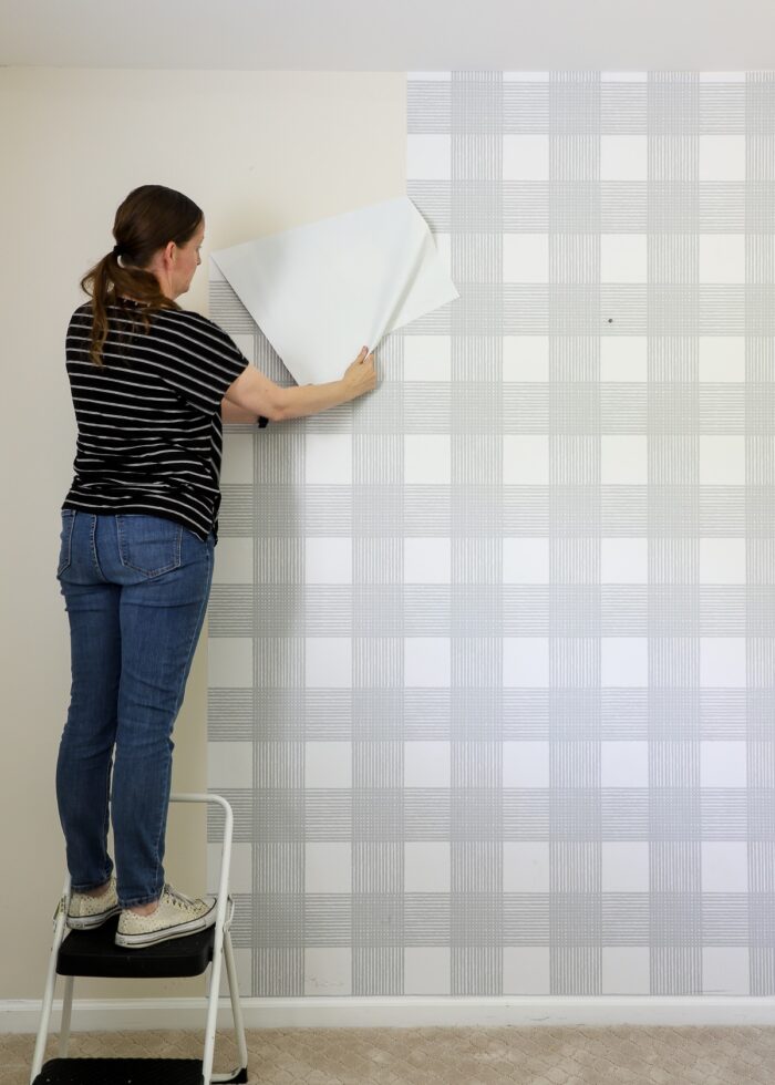 Megan on stool pulling down grey plaid wallpaper