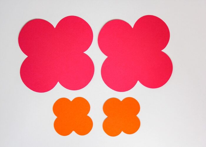 Flat pink and orange paper flowers on a white surface