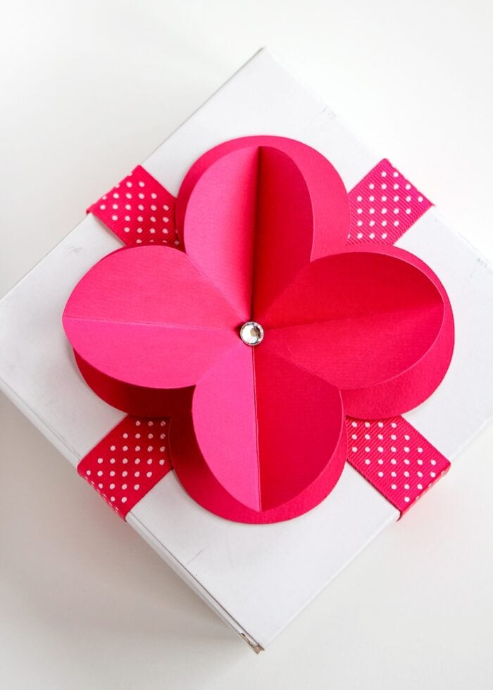 Pink 3D paper flower on top of a white gift box with pink ribbon