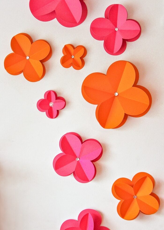 Pink and orange 3D paper flowers decorating a white wall