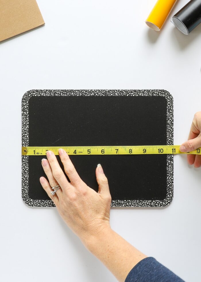 Hands measuring a chalkboard sign