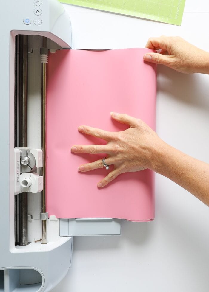 Hands loading pink Smart Vinyl into Cricut Maker 3