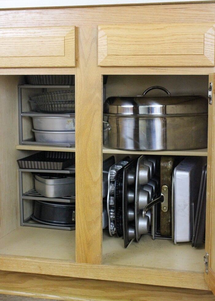 Organized baking pans inside a wooden cabinet
