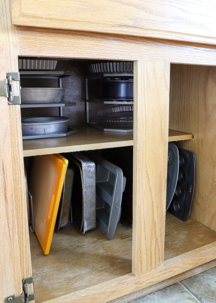 Baking pans in organizes inside a wooden cabinet