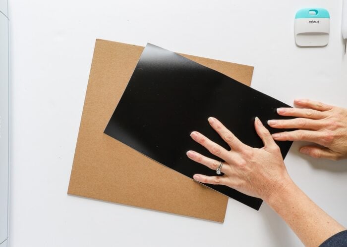 Hands placing vinyl onto chipboard