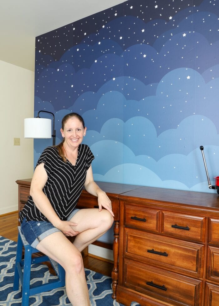 Megan sitting in front of cloud wallpaper mural