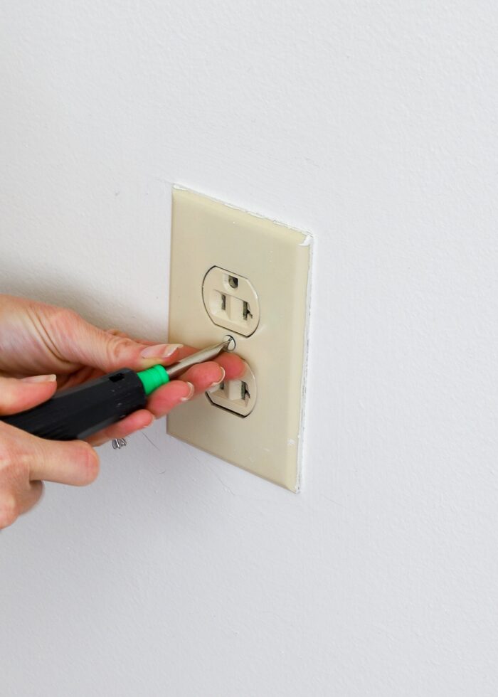 Hands removing screws on outlet plates