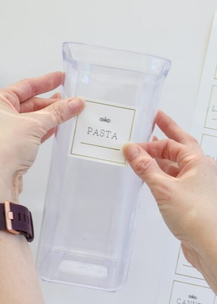 Hands placing pantry label onto empty canister