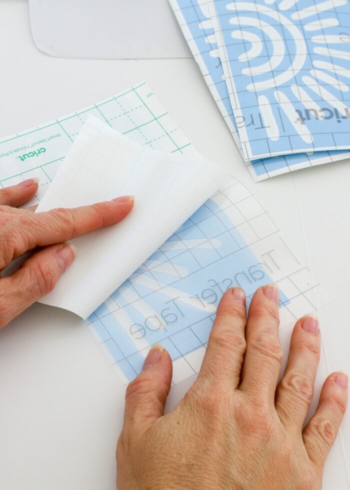 Hands peeling away paper backing off Cricut Smart Stencil