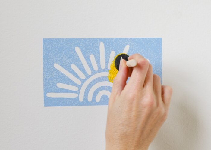 Hand applying yellow paint to sunshine stencil