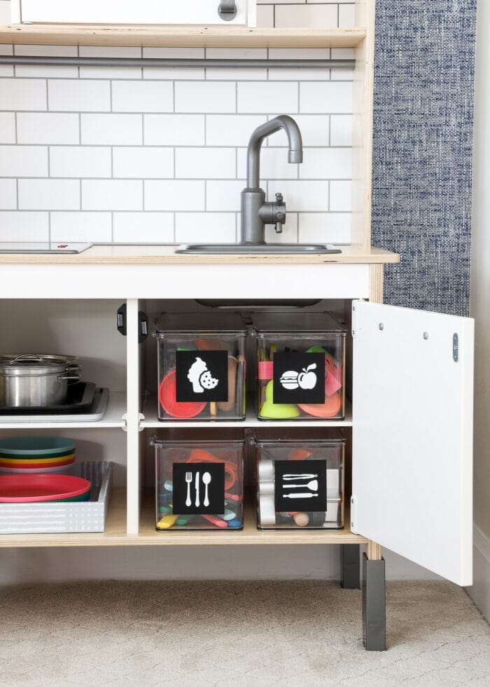 Plastic lidded boxes serving as small toy storage in a play kitchen