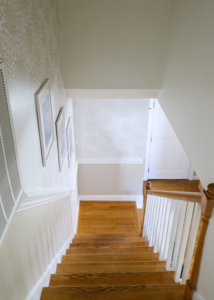 Stairwell with wooden treads and neutral floral wallpaper on the stairwell wall