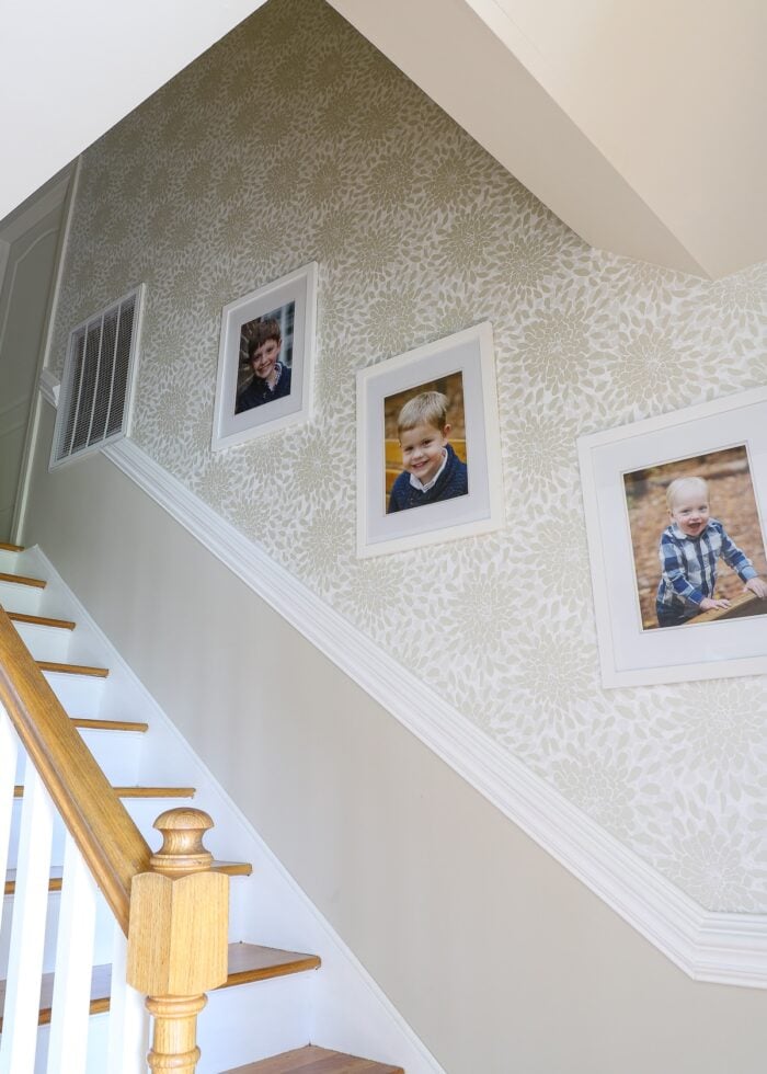 Stairwell with wooden treads and neutral floral wallpaper on the stairwell wall