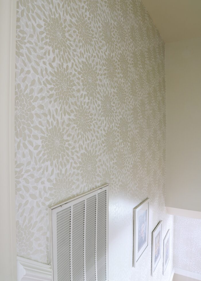 A stairwell wall covered in neutral floral wallpaper