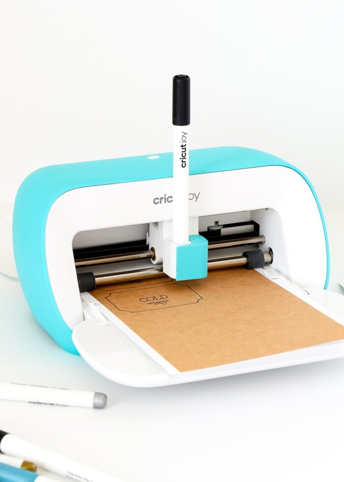 Pen loaded into Cricut Joy machine loaded with brown label paper