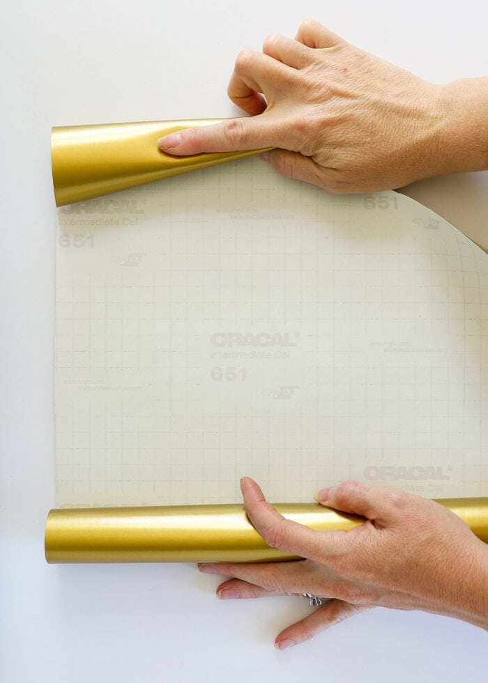 Hands holding a roll of gold Oracal vinyl open