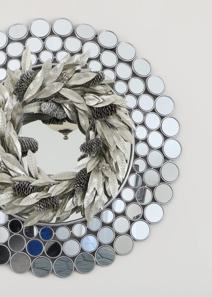 Neutral Christmas decor silver pinecone wreath on a silver mirror