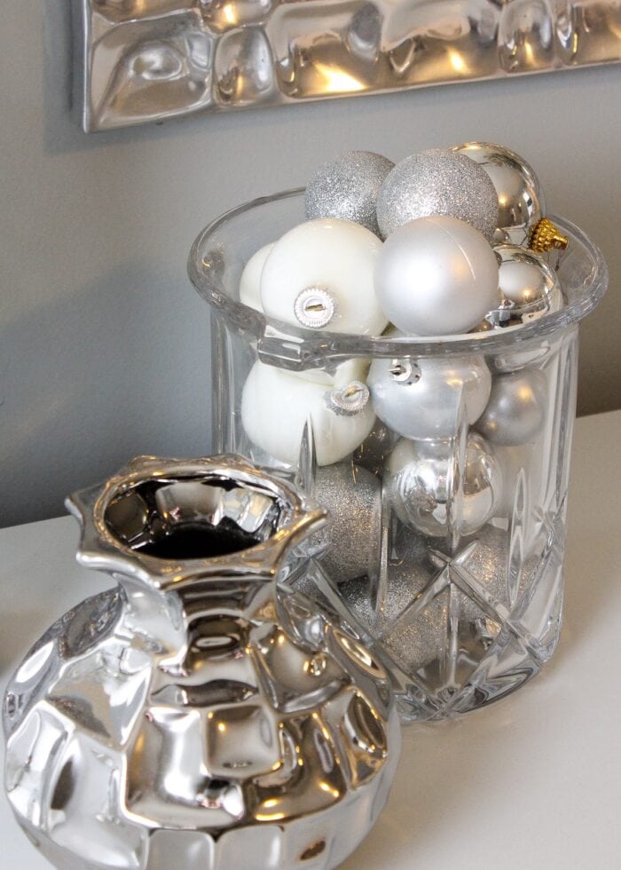 Glass vase filled with silver and white ornaments