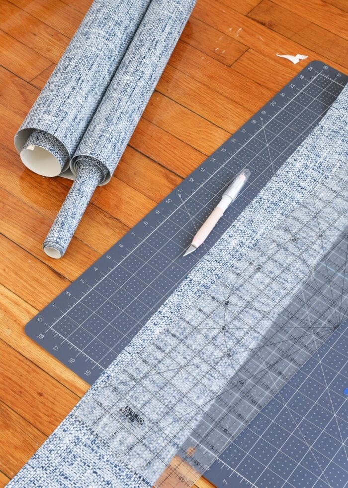 Peel and stick wallpaper cut into a strip on a cutting mat with sharp craft knife