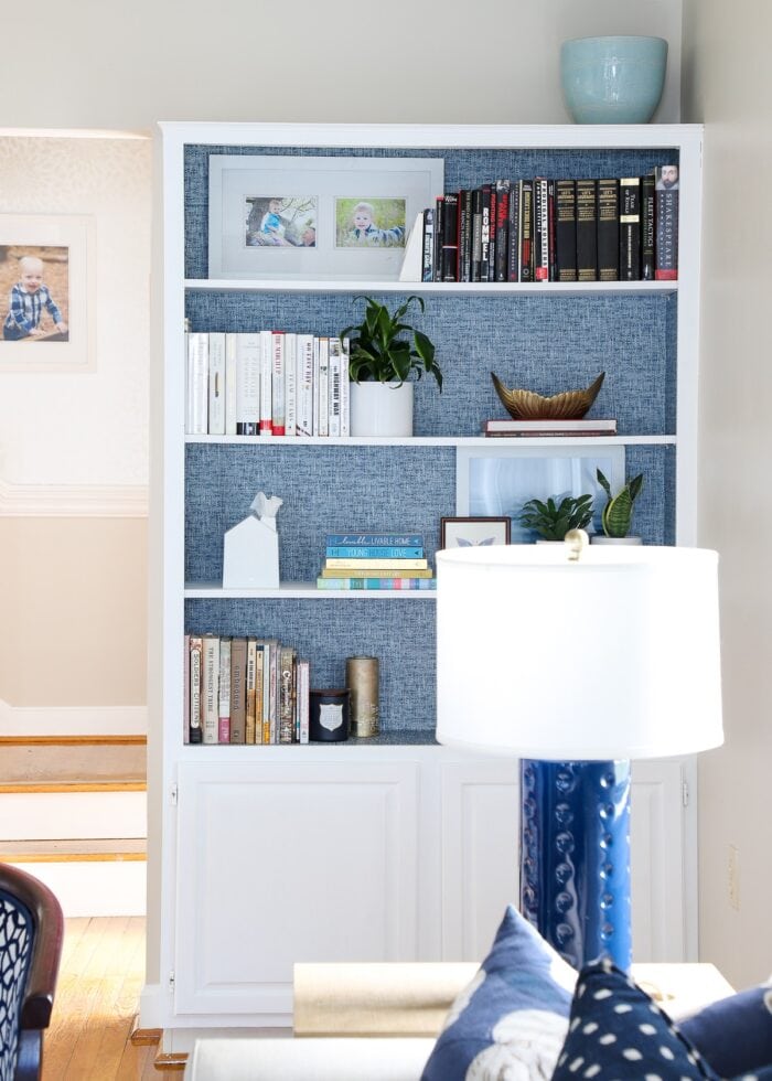 While built-in bookcases with blue peel and stick wallpaper on back