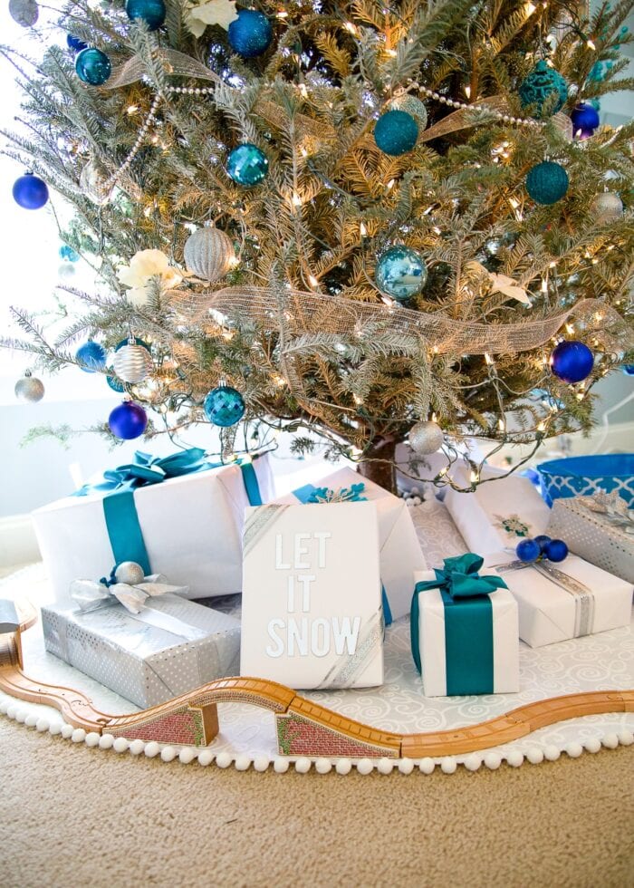 White DIY Christmas Tree Skirt with wooden train track, white packages, and turquoise ornaments