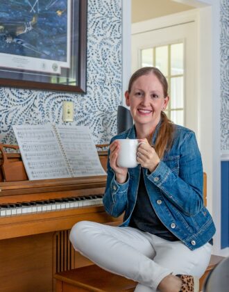 Megan holding mug next to piano