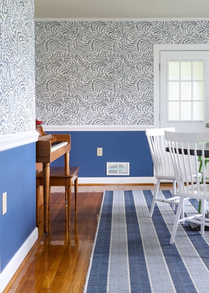 Dining room with blue paint below chair rail and wallpaper above