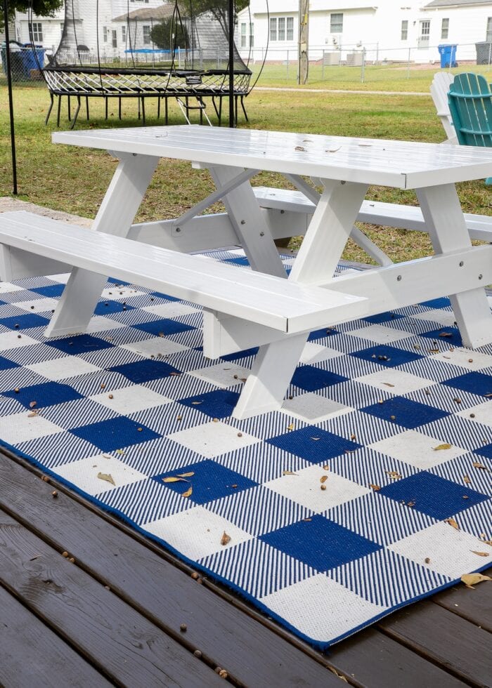 White picnic table on a blue-and-white checked rug