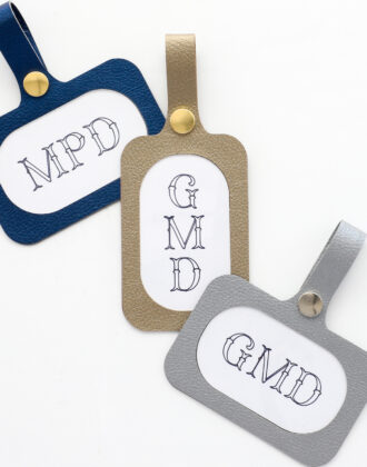 Three luggage tags made with a Cricut using faux leather with printed monogram labels on a white table surface