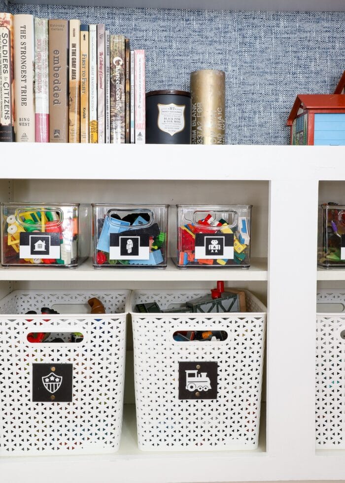 Clear toy bins on white shelf with black and white picture labels