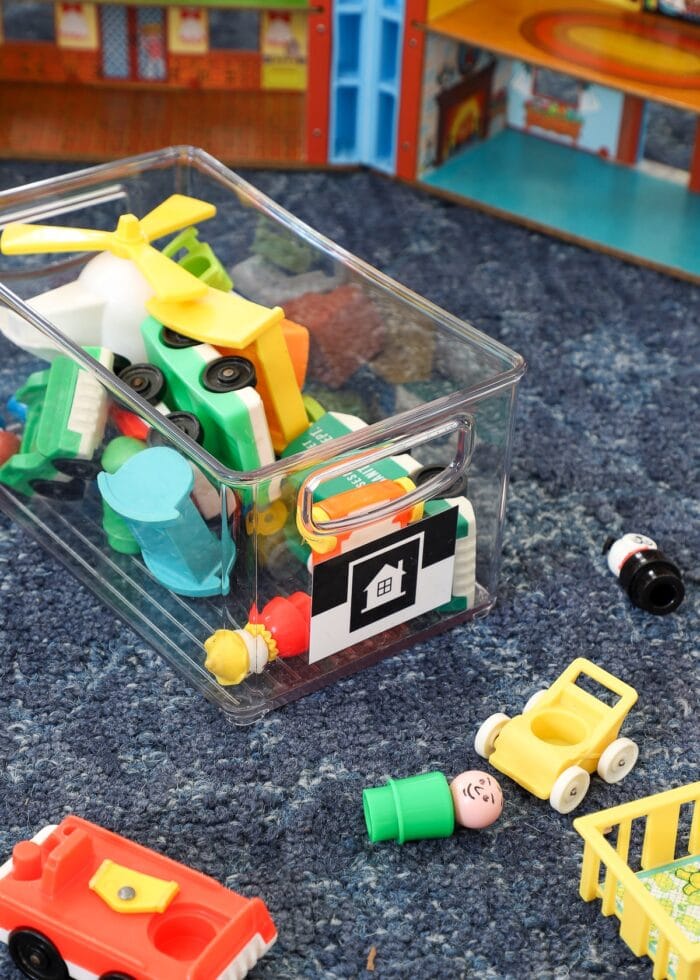 Clear toy bin on blue rug with black and white picture labels