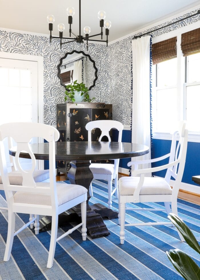Blue and white formal dining room with blue striped rug and wallpaper on the wall
