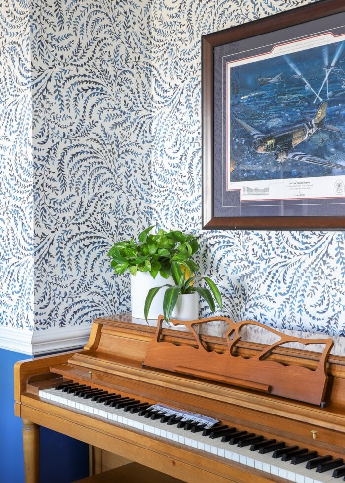 Blue and white wallpaper on the walls above a wooden piano