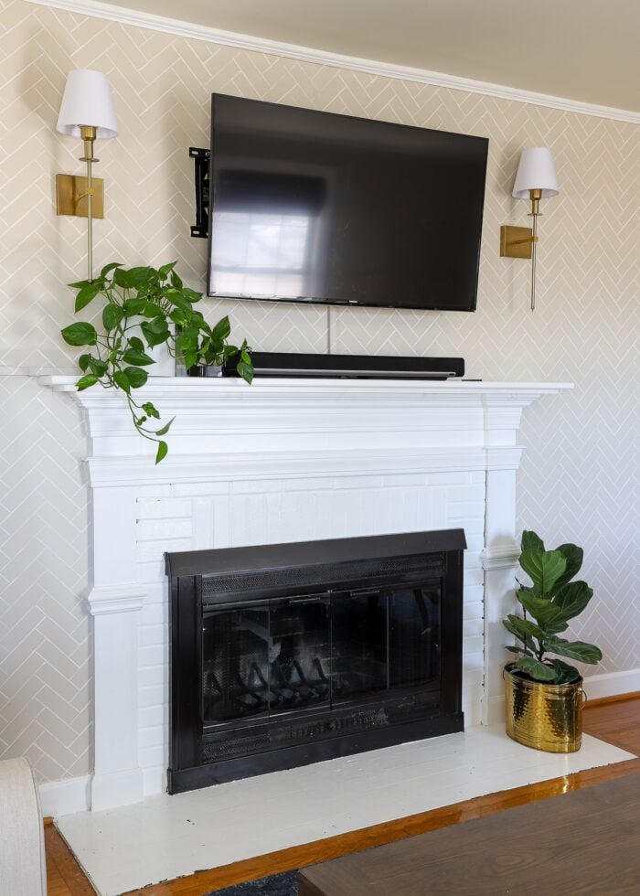 TV mounted above a white fireplace mantel with cords hidden